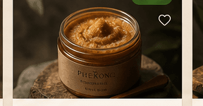 A warm amber scrub jar with botanical accents on stone and wood.